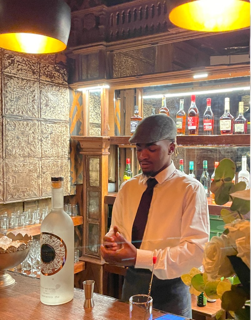 Bartender at The Alligator Bar — pressed-metal walls and premium back bar