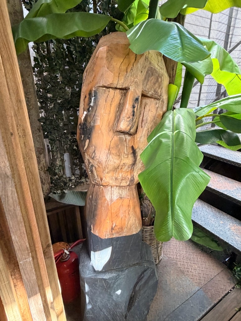 Hand-carved wooden sculpture with tropical greenery