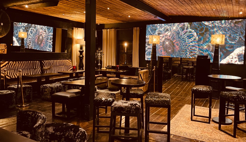 The Opium Lounge main floor — zebra banquette, high tops and kaleidoscopic LED projections